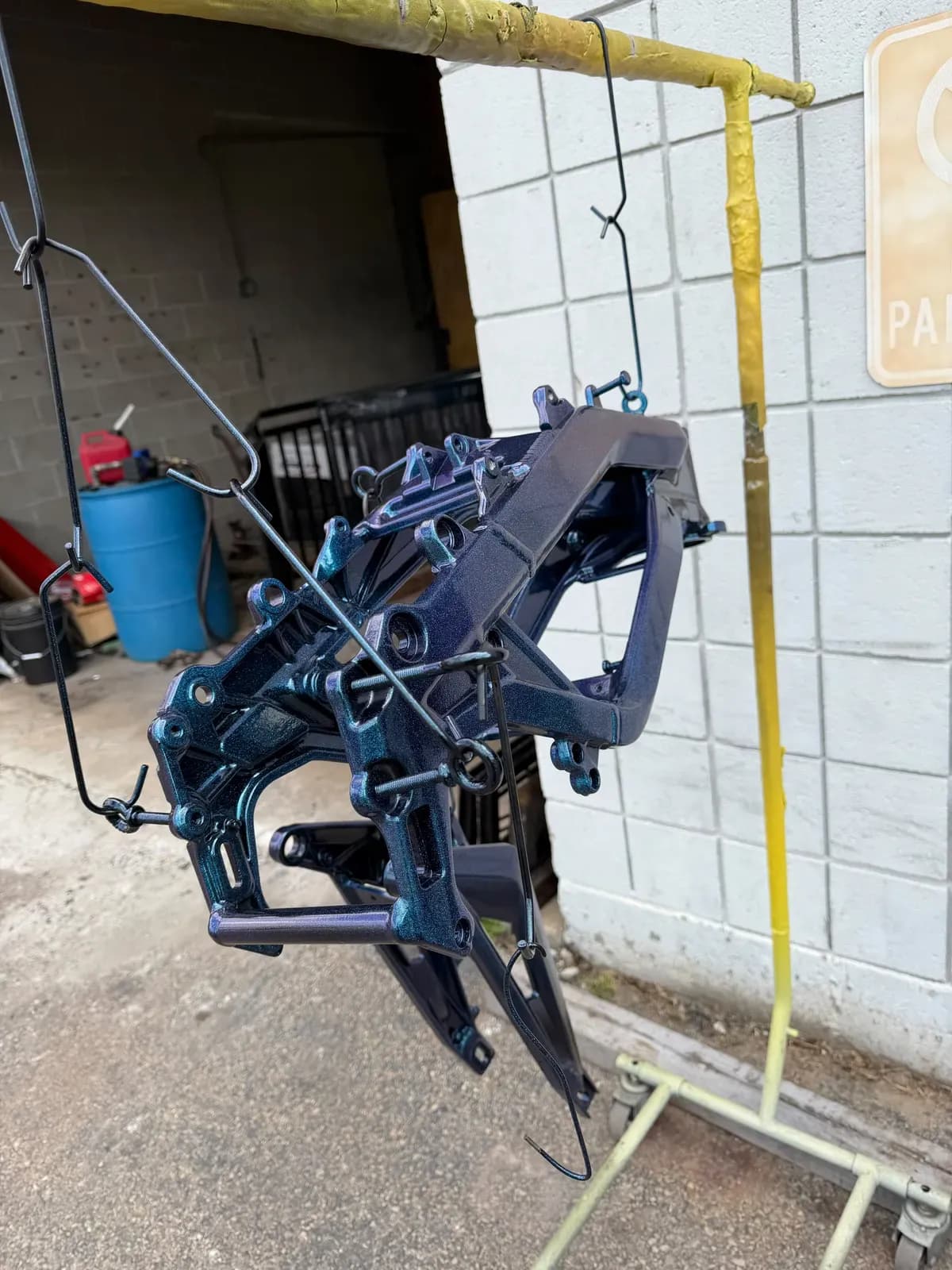 Frame parts powder coated in deep blue hanging at the shop
