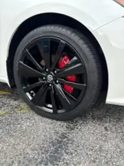 Gloss black powder coated wheels with red brake calipers on a white car