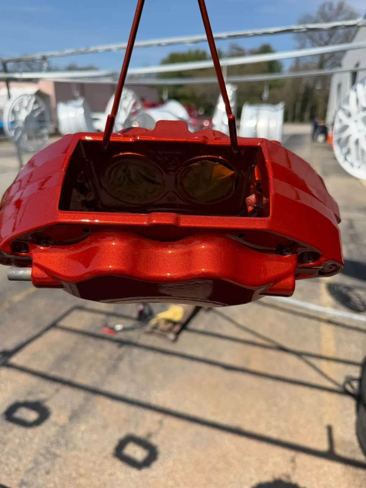 Red powder coated brake caliper hanging after curing