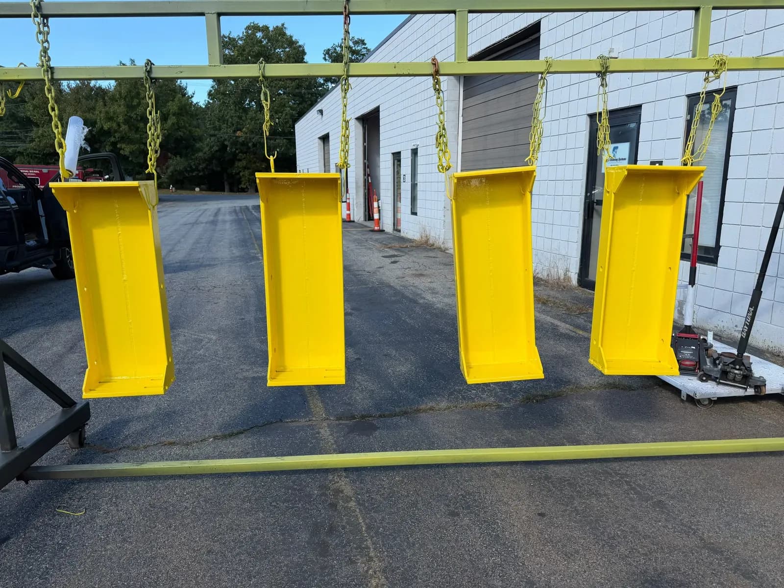 Yellow powder coated steel brackets hanging on the rack outside the Warwick shop